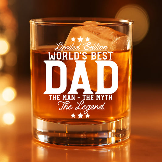  Engraved World's Best Dad whiskey glass filled with bourbon and ice, glowing in warm ambient light