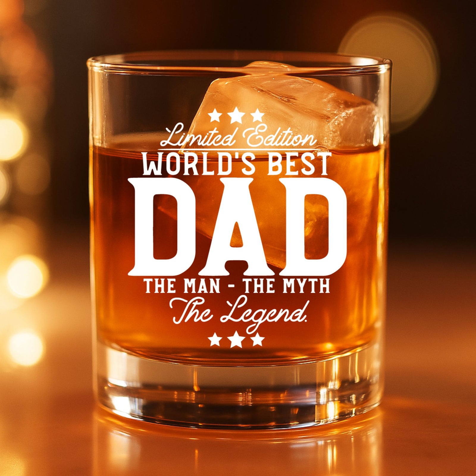  Engraved World's Best Dad whiskey glass filled with bourbon and ice, glowing in warm ambient light